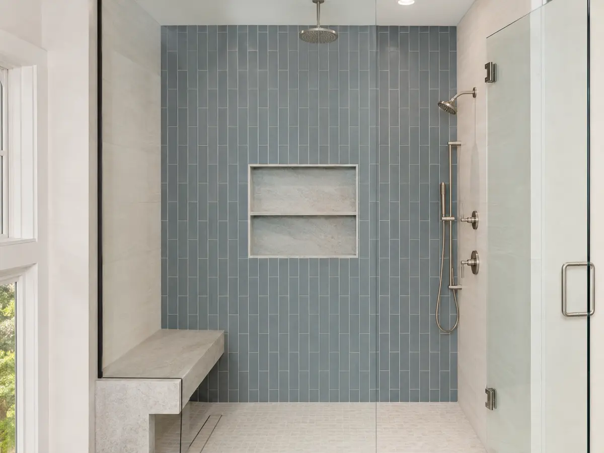 Finished walk-in shower with blue-gray tile, bench and glass enclosure